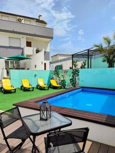 夏內卡的住宿－Villa Paraíso da Caparica，一座带椅子和桌子的游泳池位于大楼旁