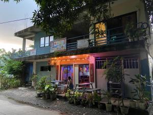 une femme debout devant un bâtiment avec des tables dans l'établissement Carib Hostel Sa-ed, à Boracay