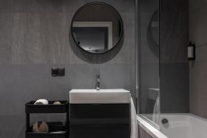 a bathroom with a sink and a mirror and a tub at Scala Apartamenty by Moderna Profit - Łąkowa 60H z parkingiem in Gdańsk +32 photos