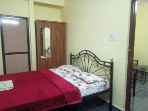 a bedroom with a bed with a red comforter at Shanaya Holiday Apartment in Benaulim