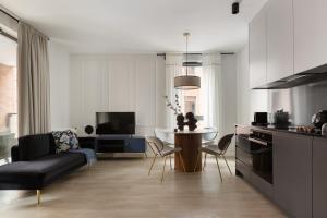 a kitchen and living room with a table and a couch at Scala Apartamenty by Moderna Profit - Łąkowa 60H z parkingiem in Gdańsk