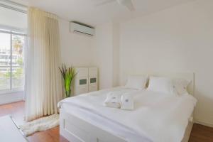 a white bedroom with a large white bed and a window at Tiran Square Haven - Herzliya Pituach in Herzliya B