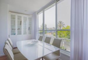een witte eetkamer met een witte tafel en stoelen bij Tiran Square Haven - Herzliya Pituach in Herzliyya B