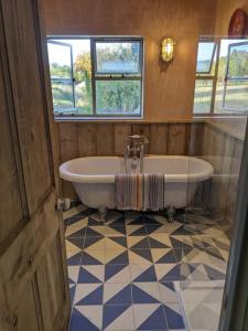 baño grande con bañera y ventana en Stylish 3 bed Cotswold cottage with stunning views, en Cheltenham