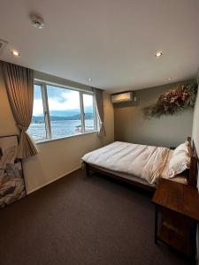 een slaapkamer met een bed en een groot raam bij The Lake House 野尻湖 in Shinano