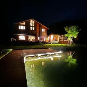 a house with a swimming pool at night at The Lake House 野尻湖 in Shinano