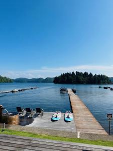 een dok met twee boten en stoelen op het water bij The Lake House 野尻湖 in Shinano