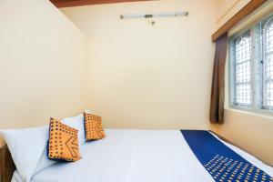 sypialnia z łóżkiem z pomarańczowymi i niebieskimi poduszkami w obiekcie OYO Renuka Lodge w mieście Belagula