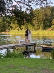una pareja besándose en un muelle en un lago en 1800 tals Sjötorp med egen strand och brygga en Åkersberga