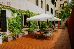 eine Holzterrasse mit Tischen, Stühlen und einem Sonnenschirm in der Unterkunft Casa Accademia in Venedig
