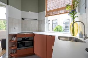 a kitchen with orange cabinets and a sink and a window at The Black Pants in Antwerp