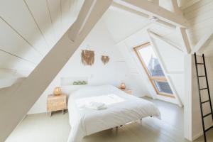 a white attic bedroom with a bed and a window at Maison Héromie - vakantiewoning Damme - 8 personen in Damme