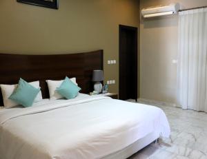 1 dormitorio con 1 cama blanca grande con almohadas verdes en L'azure Beach Resort, en Khuraybah