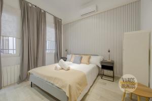 a white bedroom with a bed and a chair at Stylish Loft with 2 beedrooms en el Centro - La Latina in Madrid