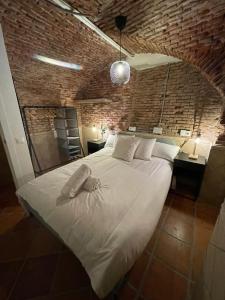 uma cama grande num quarto com uma parede de tijolos em Bajo Duplex 7pax a 5 min de Gran Via-Malasana em Madri