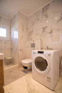 uma casa de banho com uma máquina de lavar roupa e um WC em Karlovasi Comfy Retreat em Ríva