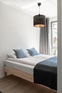a bedroom with a bed with blue pillows and a window at Scala Apartamenty by Moderna Profit- Łąkowa 60K in Gdańsk