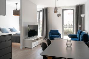 a white living room with a tv and a bed at Scala Apartamenty by Moderna Profit- Łąkowa 60K in Gdańsk