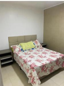 a bedroom with a bed with a floral comforter at Pousada da Vovó Ideni Nova Tramandaí in Tramandaí