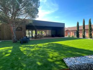 una casa con un gran patio con césped verde en Hôtel & Séminaire Le Patio Occitan - Toulouse Ouest - Francazal, en Cugnaux