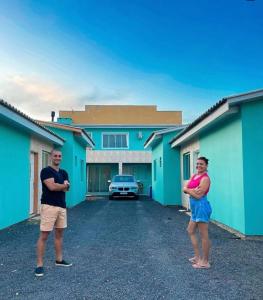 two people standing in front of a blue building at Pousada da Vovó Ideni Nova Tramandaí in Tramandaí