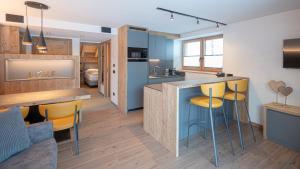 a kitchen and living room with blue cabinets and yellow bar stools at Chalet Aria Pura in Livigno