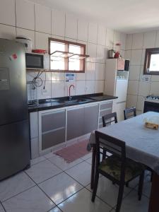 a kitchen with a table and a sink and a refrigerator at Ramos Acomodações in Búzios