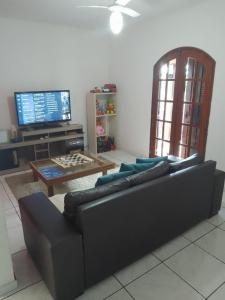 sala de estar con sofá, mesa y TV en Ramos Acomodações, en Búzios