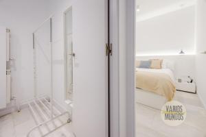 a white bedroom with a bed and a mirror at Cool Duplex Bajo Apt 7pax cerca de Tirso de Molina in Madrid