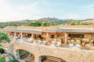 a view of a stone building with chairs and tables at Hotel Pitrizza, Costa Smeralda in Porto Cervo