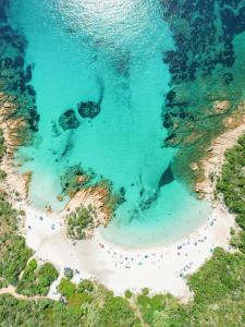 eine Luftansicht auf einen Strand mit Menschen im Wasser in der Unterkunft Hotel Pitrizza, Costa Smeralda in Porto Cervo