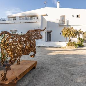 eine Metallstatue einer Kuh auf einem Tisch vor einem Gebäude in der Unterkunft Hotel Rural Ganadería Virgen María in Sevilla