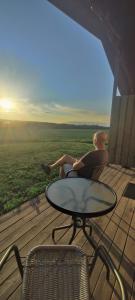 un homme assis sur une terrasse en regardant le coucher du soleil dans l'établissement Stuga utanför Skövde 3, à Skövde