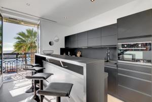 una cocina con taburetes y armarios en blanco y negro en Cocoon in Cannes Sea View., en Cannes