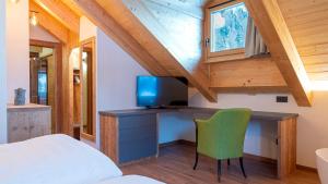 a bedroom with a desk with a tv and a chair at Chalet Aria Pura in Livigno