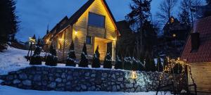 ein Haus mit Weihnachtslichtern im Schnee in der Unterkunft Lodge Sisters in Sekulić 
