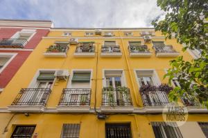 Centrico and Cozy Apt para 9pax en Calle San Dimas في مدريد: مبنى اصفر مع نوافذ وشرفات