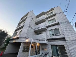 a tall white building with stairs on it at HS平岸 HSHiraghishi in Minami-jūichijō