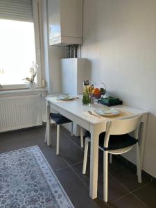 een kleine keuken met een witte tafel en stoelen bij Appartement des 3 frontières in Saint-Louis