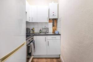 a kitchen with white cabinets and a sink at LiveStay Cozy One Bedroom Apartment in Brixton in London