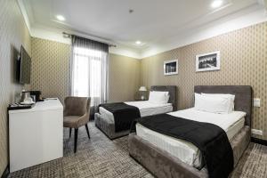 um quarto de hotel com duas camas e uma cadeira em Wall Street Maestro em Odessa