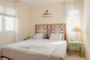 a bedroom with a white bed with a wooden headboard at Villa Bonita in Corralejo