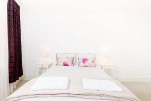 a white bedroom with a white bed and two tables at City Centre - New Street in Birmingham
