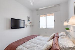 a white bedroom with a bed and a flat screen tv at Sandra Amadores in Puerto Rico de Gran Canaria