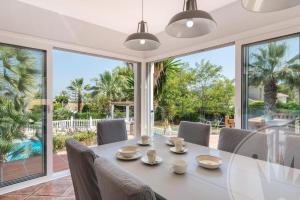 une salle à manger avec une table, des chaises et une grande fenêtre dans l'établissement La Manga Club Resort - Individual Villa 439, à Atamaría