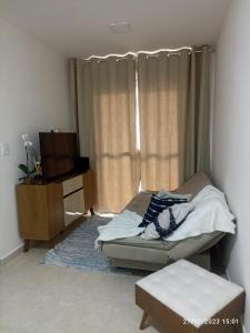 a bedroom with a bed and a tv and a couch at AP da Karine a 700 metros da praia da Guilhermina in Praia Grande