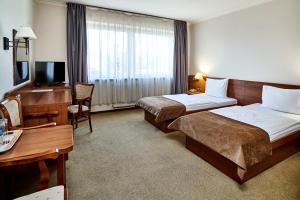 a hotel room with two beds and a desk at Hotel Stara Poczta in Tychy
