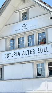 un bâtiment blanc avec un panneau indiquant osteria après abattage dans l'établissement Alter Zoll, à Teufen
