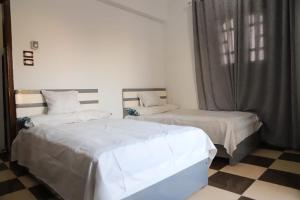 a bedroom with two beds and a checkered floor at Mountain House in Luxor