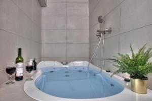 סוויטת גן עדן - Gan Eden Suite في صفد: حوض استحمام مع كأسين من النبيذ ونبتة